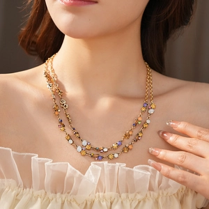 Detailed close-up of double-layer gold necklace with colorful crystals on a model