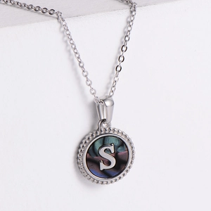 Close-up of silver necklace with an S-letter pendant and iridescent dark shell inlay