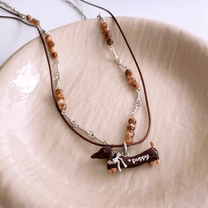 Detailed view of dachshund pendant with white PUPPY text on a beige ceramic tray