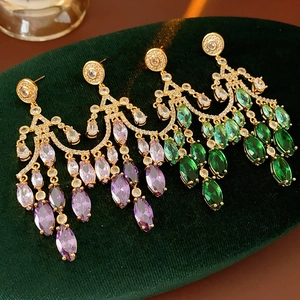 Close-up of gradient zircon teardrop earrings in purple and green on velvet
