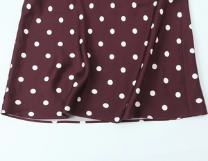 Close-up of elegant red-brown polka dot dress fabric with flowing drape and soft texture