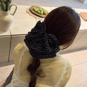 Gros plan d'une pince à cheveux vintage à pois noirs avec un nœud sur une queue de cheval