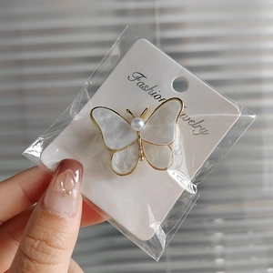 Elegant butterfly brooch with pearl center and golden edges on fashion jewelry card