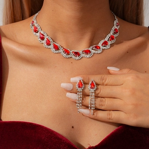 Detailed view of model wearing vintage pear-cut red gemstone necklace and tassel earrings