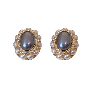 Vintage style gold earrings featuring a grey center stone with pearls and rhinestones