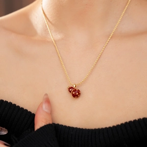 Detailed close-up of 18k gold plated necklace featuring a red gourd pendant on model neck