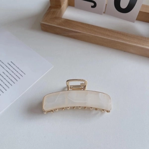 Detail of a 7.5cm beige marble texture hair claw clip with elegant golden metal frame