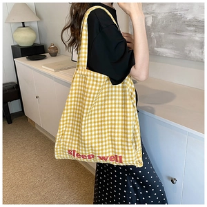 Detail of yellow and white checkered tote bag featuring Sleep Well red embroidery
