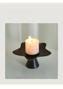 Close-up of star-shaped matte black candle holder with a white scented pillar candle