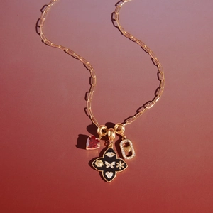 Goldene Halskette mit Herzanhänger, Kleeblatt und Pavé-Rahmen auf rotem Hintergrund