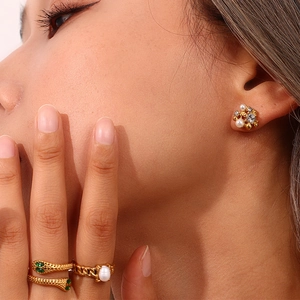 Detail of 18K gold plated floral earrings with pearls and snake ring on model