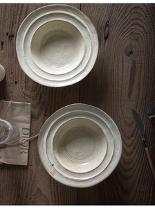 Close-up of handmade stoneware bowls with spiral texture and rustic iron spots on wood