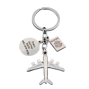 Travel keychain with airplane, passport and inspirational quote charms on white background