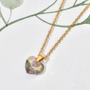 Macro view of gold heart pendant with colorful cubic zirconia and thin metal chain