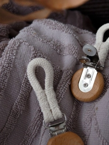 Detail of woven cotton rope with metal clip and natural wood base for towel hanging