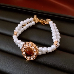 Dettaglio del bracciale vintage a doppia fila di perle con gemma ambra e chiusura a fiore