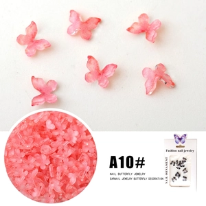 Macro detail of 3D resin butterfly nail art charms in orange-pink gradient finish