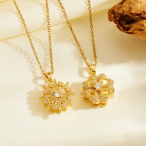 Detail of golden spinning flower pendant with zircons on white silk background