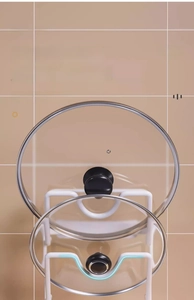 Detail of white wall-mounted pot lid rack with U-shaped double slots for secure storage