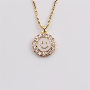 Detailed close-up of a gold-plated necklace with a white enamel smiley face pendant