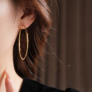 Vue macro de boucles d'oreilles créoles dorées avec une texture en métal martelé unique