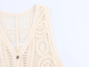 Dettaglio del gilet all'uncinetto color crema con scollo a V e bottone in legno