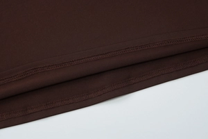 Detail of dark brown knitted fabric showing premium stitching and fine sewing texture