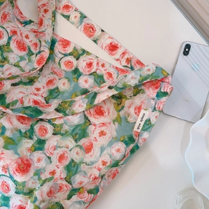 Dettaglio della borsa tote in tela con stampa floreale a olio e etichetta logo