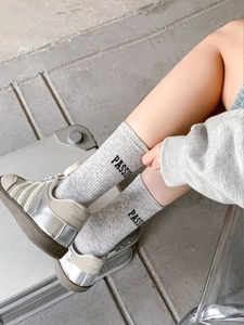 Detail of grey combed cotton crew socks with PASSION text paired with silver sneakers