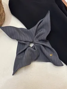 Detailed view of grey striped fabric hair scrunchie with a round gold metal button