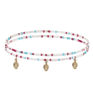 Détail de perles colorées et pendentifs coquillages dorés sur une chaîne de taille bohème