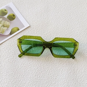 Detail view of stylish green oval sunglasses with translucent frames on white textured background