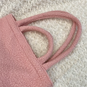 Dettaglio dei manici della borsa bouclé rosa con cuciture e trama di alta qualità
