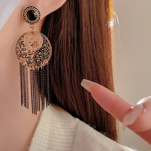 Vintage gold coin earrings with black gemstone and tassel fringe worn by model