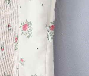 Detail shot of invisible side zipper on cream floral smocked dress with lace accents