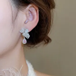 Silver butterfly earrings with pink water-drop crystal pendant worn by a model