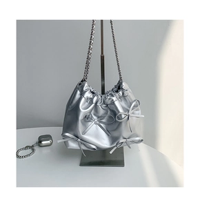 Detailed view of silver drawstring bag with bow accents and metallic chain strap