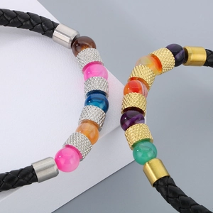 Dettaglio del bracciale in pelle nera intrecciata con perle colorate e distanziatori