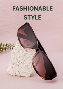 Detail of square tea brown sunglasses on a decorative stone with a leaf accent