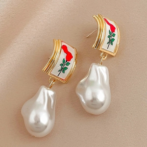 Detailed macro of vintage rose enamel earrings with baroque pearls on silk fabric