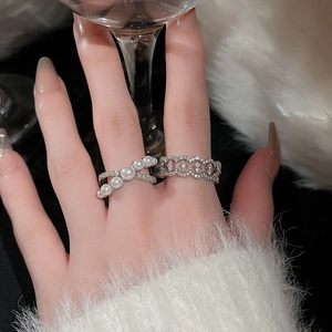 Detail of silver crisscross pearl ring and hollow zircon band on finger with elegant vibe