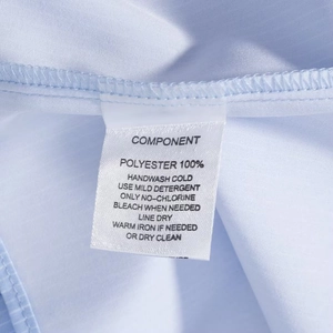 Detail of care label on light blue polyester shirt with clear washing instructions