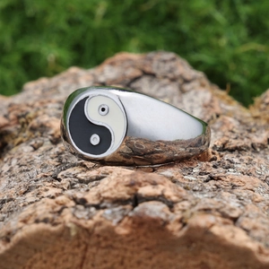 Polished stainless steel Tai Chi Yin Yang ring displayed on a natural bark surface
