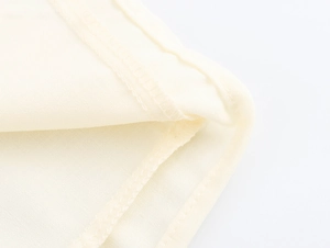 Detailed close-up of high-quality stitching and soft beige fabric on a French square neck dress