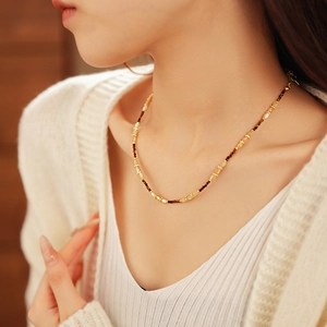 Gros plan d'un collier de perles fleurs aux tons ambre et marron sur un mannequin