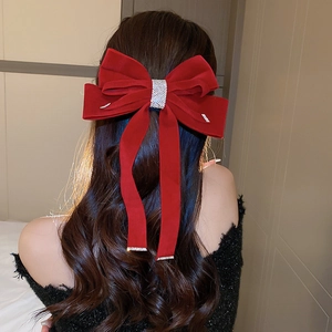Close-up of red velvet bow hair claw clip with rhinestones on a woman's hair