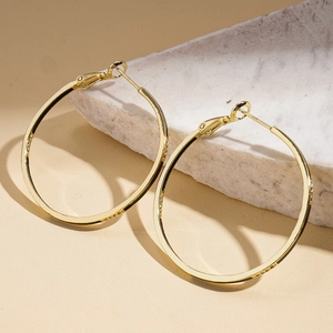 Détail des boucles d'oreilles créoles dorées à l'or 14 carats sur un socle en pierre