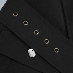 Détail de robe noire avec cinq oeillets en métal doré et un cristal rectangulaire poli