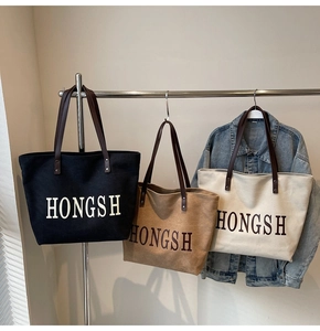Three large canvas tote bags in black, khaki, and cream colors with dark brown leather handles