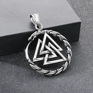 Macro detail of Viking Valknut pendant with Ouroboros ring on black leather texture